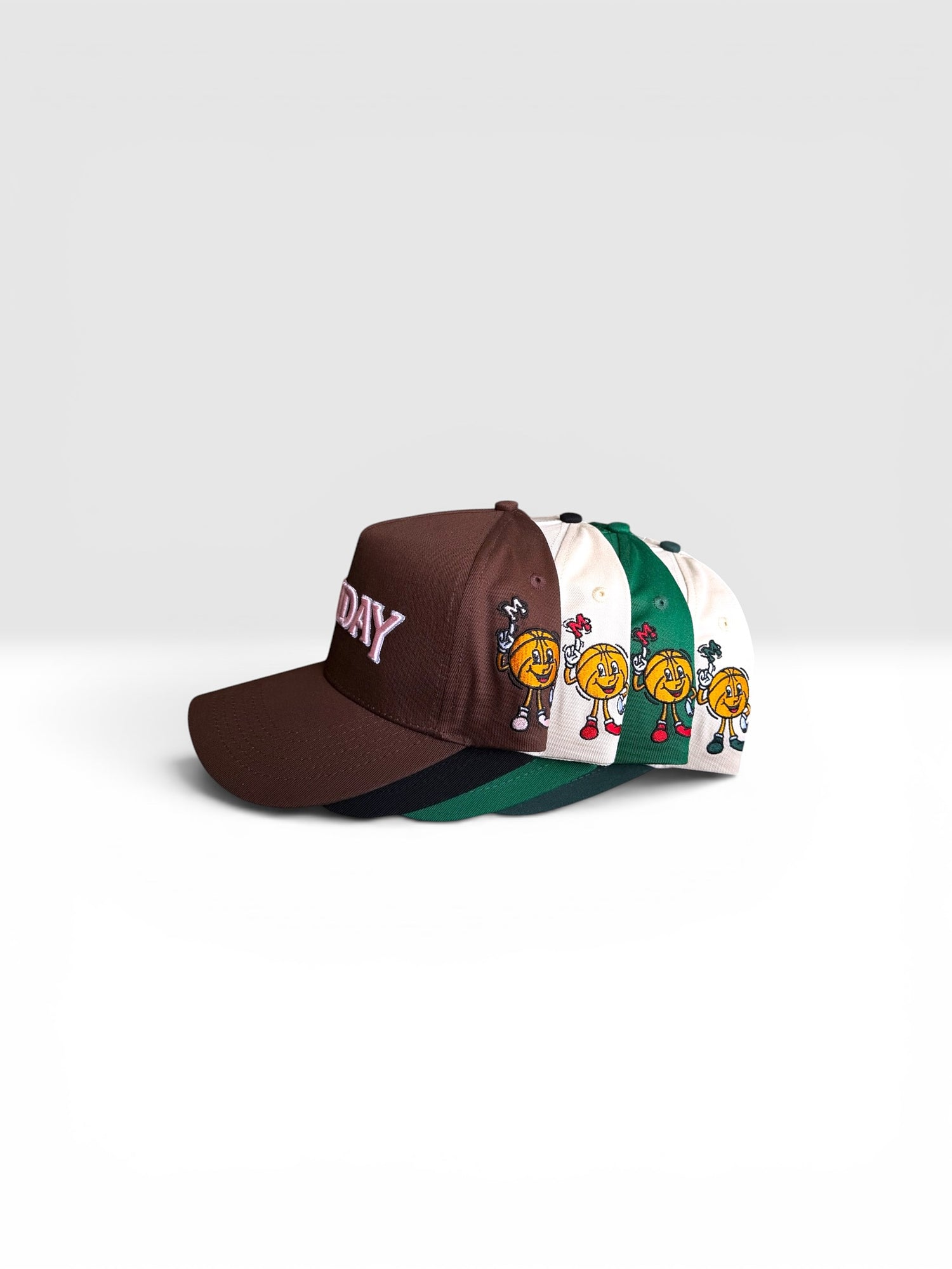 Four Monday baseball caps with different designs on a light gray background