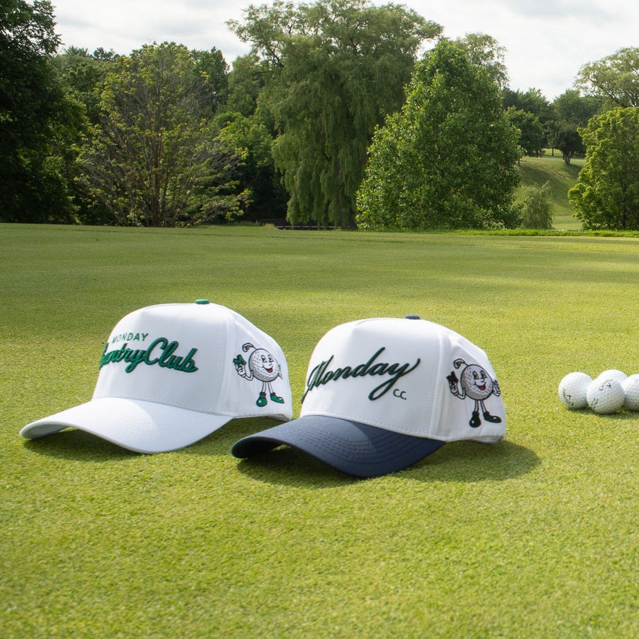 Two golf hats and a brown bag on a golf course with trees in the background